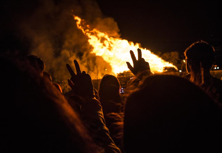 Students looking on to the homecoming bonfire; making the eagle claw.